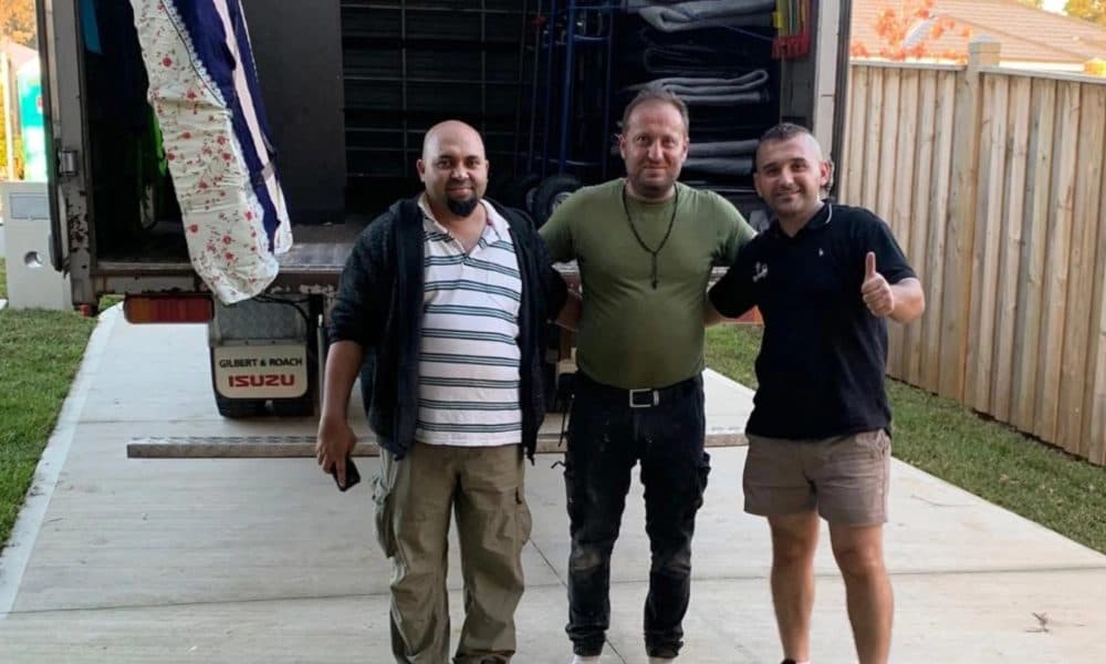 Removalist giving a thumbs up with happy customers at the back of the moving truck