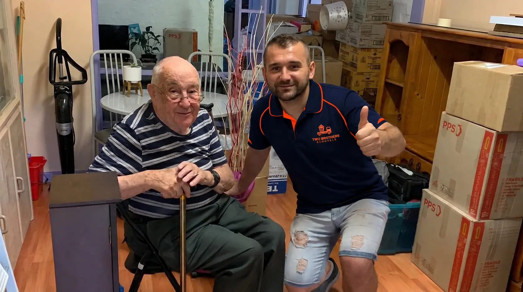 Two Brothers removalist giving a thumbs up alongside an elderly customer in his new home