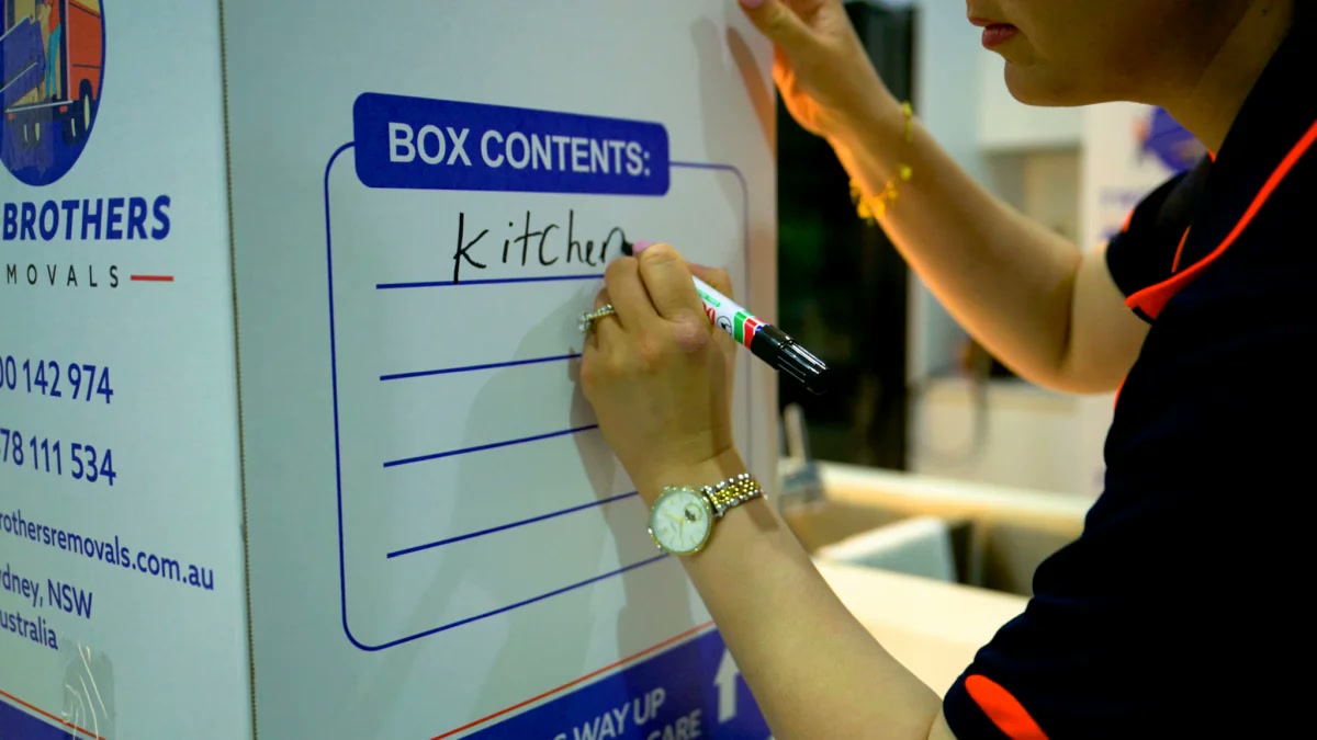 Crew member clearly labelling a Two Brothers Removals moving box for the kitchen