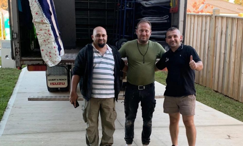 Removalist giving a thumbs up with happy customers at the back of the moving truck