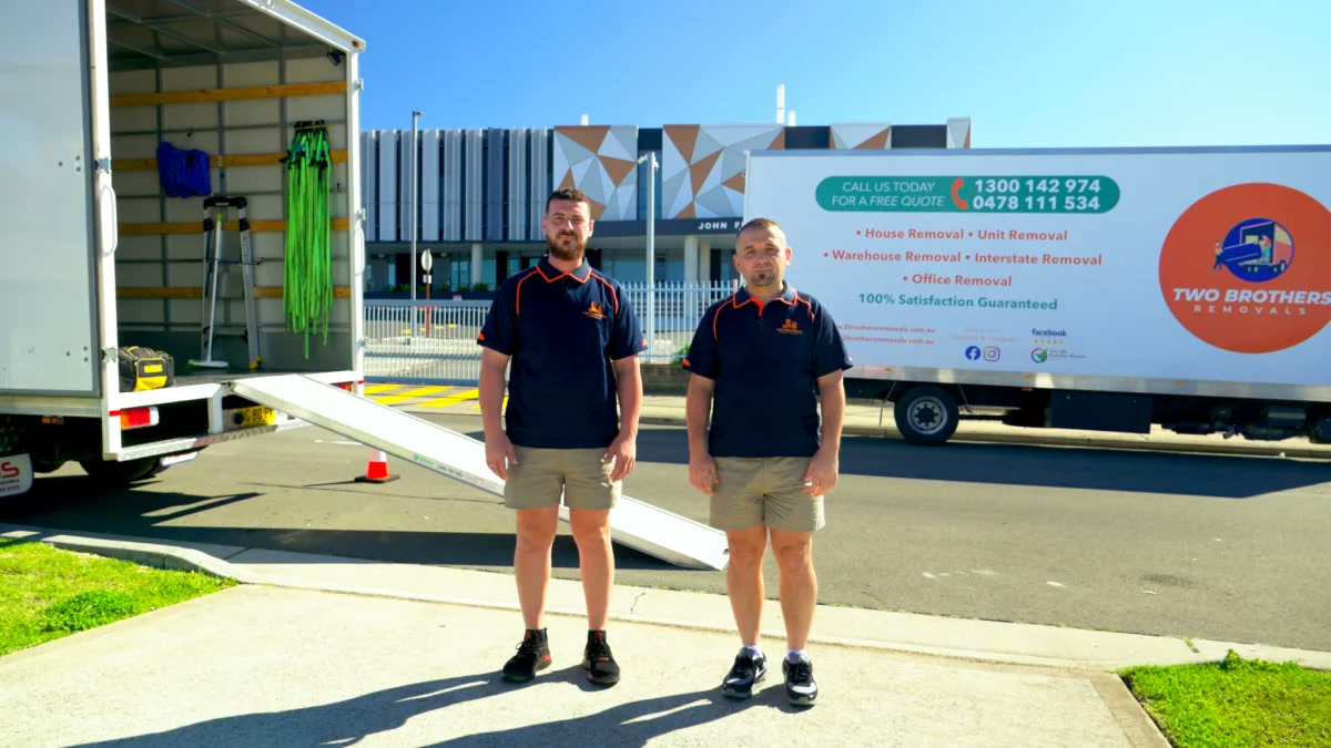 Two Brothers Removals crew in uniform beside the truck