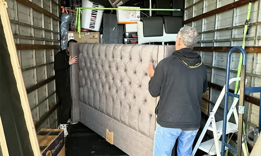 Removalists loading upholstered furniture into a moving truck